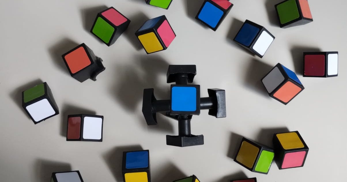 A completely disassembled Rubik's Cube, its colored pieces lying scattered atop a white background