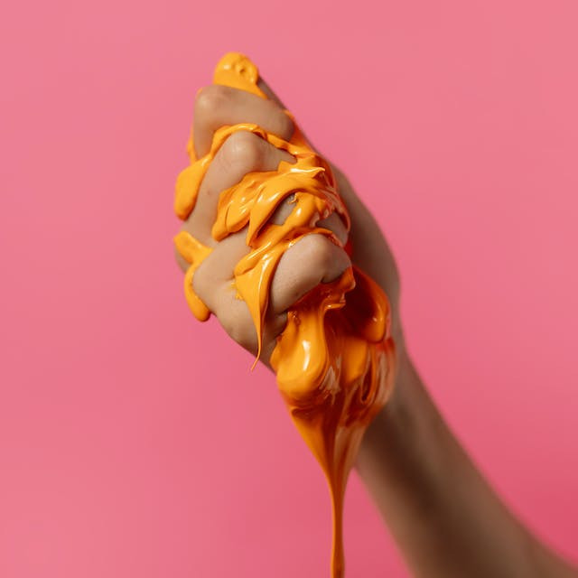 Hand squeezing orange, gooey slime